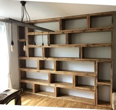 an empty room with some wooden shelves on the wall and a light fixture hanging from the ceiling