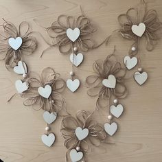 several white hearts and bows are hanging on a wooden table with string attached to them