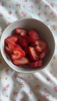 a white bowl filled with sliced strawberries on top of a bed