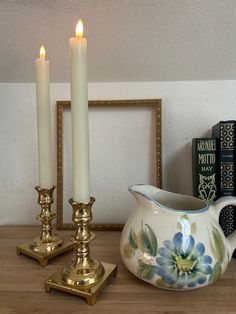 two candles are sitting on a table next to some books and a vase with flowers