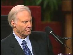 an older man wearing a suit and tie sitting in front of a microphone with his eyes closed