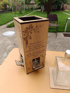 a wooden box sitting on top of a table next to an empty glass bottle with writing on it