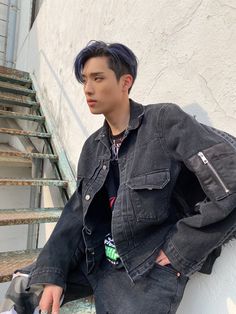 a young man with blue hair sitting on the steps wearing a denim jacket and jeans