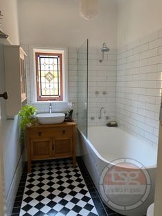 a bathroom with black and white checkered flooring next to a bathtub in the corner