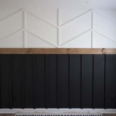 an empty room with black painted walls and white paneling on the wall, along with a radiator