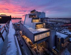 an aerial view of a building at dusk with snow on the ground and lights in the windows