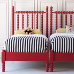 two red twin beds with black and white bedding, one has a teddy bear on it