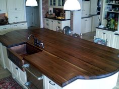 a large kitchen with an island made out of wood and white cabinets is pictured in this image