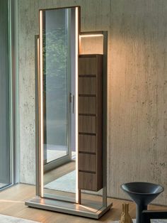 a mirror sitting on top of a wooden floor next to a table with a vase