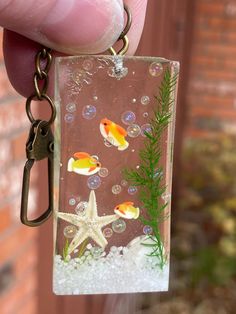 a hand holding a keychain with fish and bubbles on it