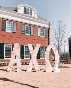 the letters are painted pink and white in front of a brick building