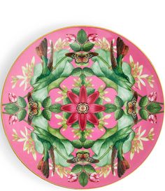 a pink plate with green leaves and flowers on the rim, painted in bright colors