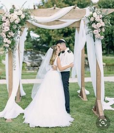 a bride and groom standing under an arch with flowers on it at their wedding ceremony