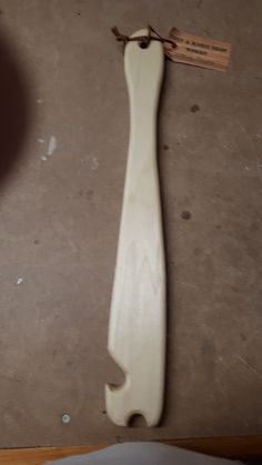 an unfinished piece of wood sitting on top of a floor next to a knife blade