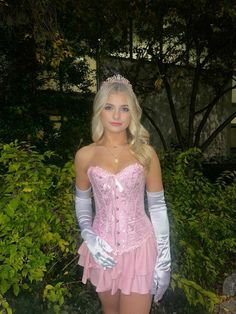 a woman in a pink corset and gloves posing for the camera with her hands on her hips