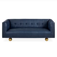 a blue leather couch with gold legs and buttons on the armrests, against a white background