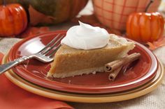 a slice of pie on a plate with whipped cream and pumpkins in the background