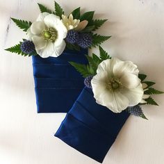 two blue vases with white flowers and green leaves