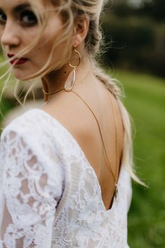 a woman in a white dress is wearing large gold hoop earrings and an intricate necklace