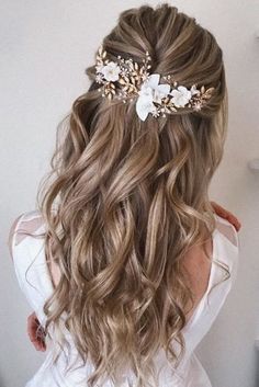 the back of a woman's head with long wavy hair and flowers in her hair