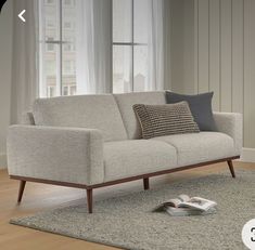 a couch sitting on top of a wooden floor next to a rug and window sill