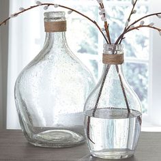 two glass vases with flowers in them on a table