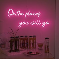 a neon sign that reads, oh the places you will go with drinks and fruit