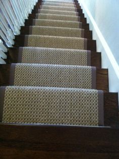 the carpeted stairs are lined with white railings and wood handrails on both sides