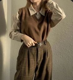 a young woman is posing for the camera wearing a sweater and wide legged pants with her hands on her head