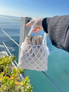 a hand is holding a small bag over the water