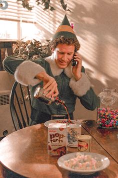 a man sitting at a table talking on a cell phone with candy in front of him