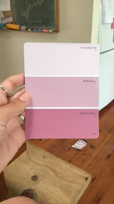 a hand holding a pantone color swatch in front of a refrigerator