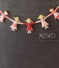 three dolls are hanging on a chalkboard with the word xoxo written below them