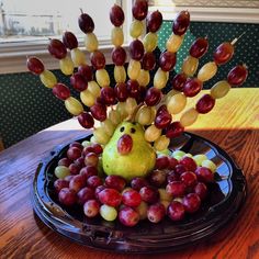 a plate with grapes and fruit in the shape of a hedgehog sitting on top of it