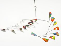 a multicolored metal wind chime hanging on a white wall