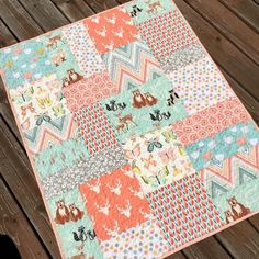 a colorful patchwork quilt on a wooden deck with an animal motif in the center