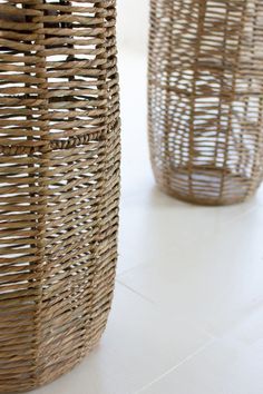 two wicker baskets sitting next to each other on a white tablecloth covered floor