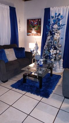 a living room decorated for christmas with blue and white decorations on the walls, couches, coffee table and rugs