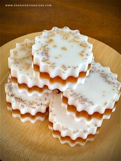 four pieces of soap sitting on top of a wooden plate with white frosting and sprinkles