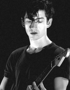 black and white photograph of a young man playing an electric guitar with his eyes closed