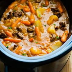 a crock pot filled with stew and carrots