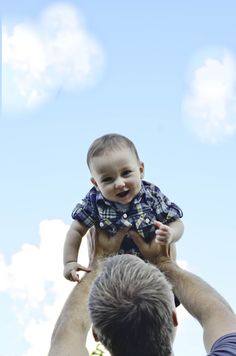 a man holding a baby up in the air with his hands on top of him