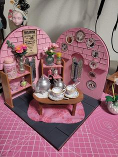 there is a doll house made to look like a tea set with pink furniture and accessories