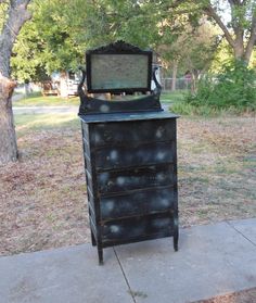 an old dresser with a mirror on top of it in the middle of a sidewalk