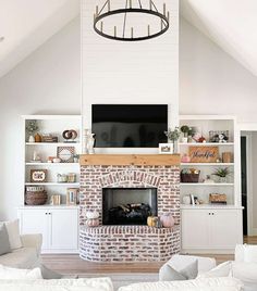 Celebrate a fireplace wall that reaches up to vaulted ceilings. A design like this has the potential to showcase an upper and lower portion with two different textures, like this wall which features a brick fireplace connected to a white shiplap wall. A wooden mantel separates the two materials, complementing the fall decor that appears on the surrounding white built-in shelves...   Image: farmhouseoncobbs