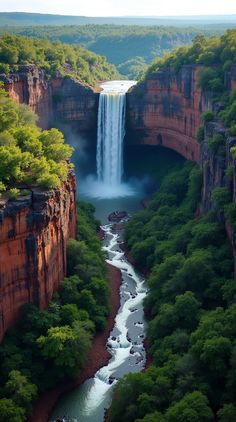 an aerial view of a waterfall in the middle of a river surrounded by green trees