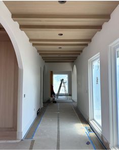 an empty hallway with white walls and blue tape on the floor is being worked on