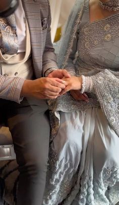 two people sitting next to each other wearing wedding attire and holding hands with one another