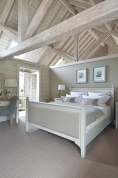 a large bed sitting under a wooden roof in a bedroom next to a desk and chair