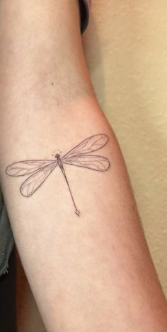 a small dragonfly tattoo on the arm